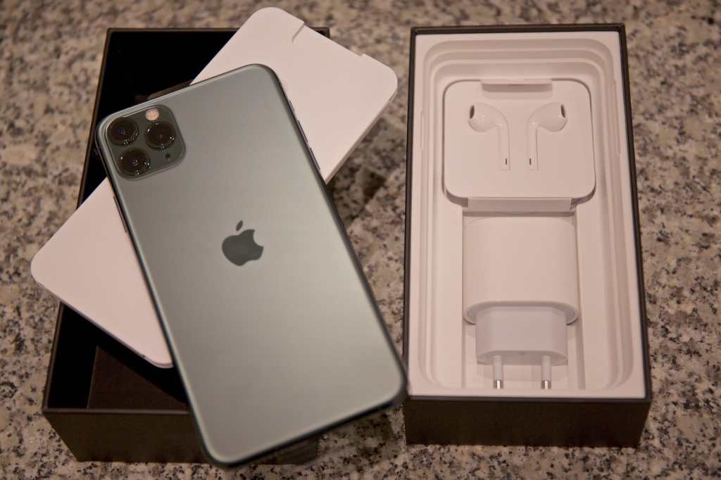 Close-up of iphone 11 pro outside from the box with airpods and charger
